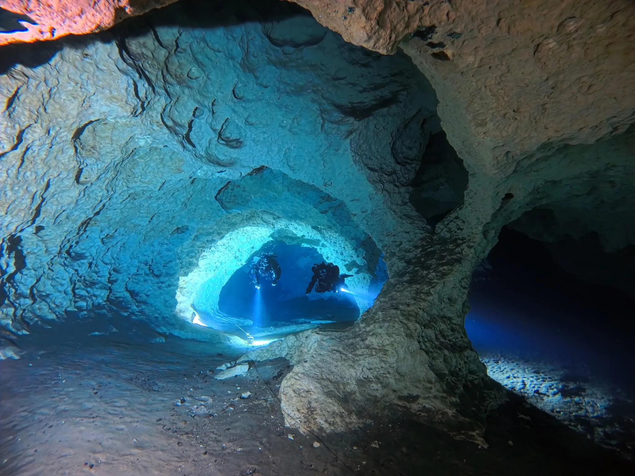 Two cave divers with dive lights inside a Peacock Springs passage, Florida