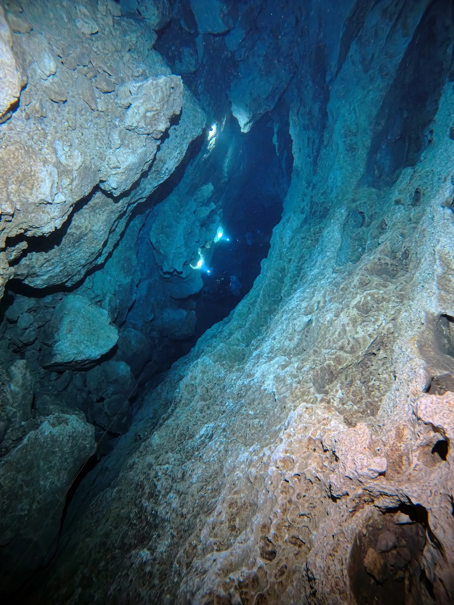 Diver light beam in a narrow vertical cave crack at Peacock Springs, Florida